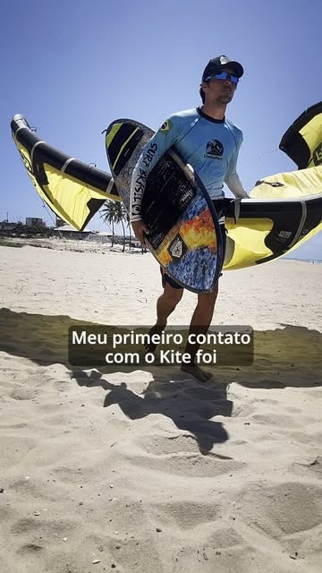 Instrutor da escola carregando prancha e kites na praia
